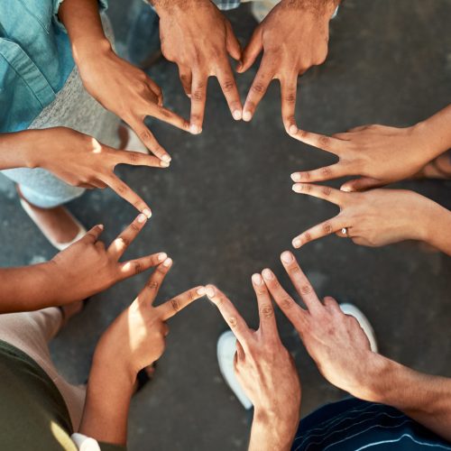 We are all stars is some form of way. High angle shot of an unrecognizable group of work colleagues forming an unique huddle with their fingers while standing in the office at work