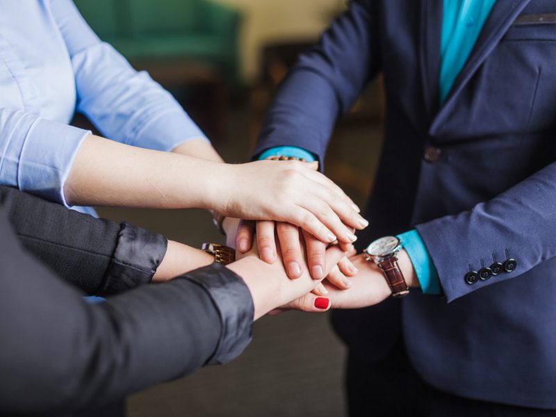 people-standing-office-holding-hands-together